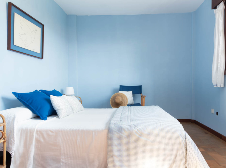 Dormitorio con paredes pintadas de azul y cama de matrimonio