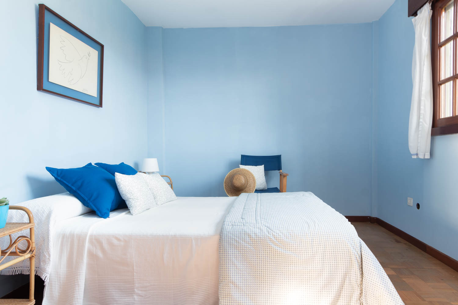 Dormitorio con paredes pintadas de azul y cama de matrimonio