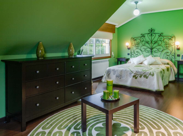 Dormitorio decorado en verde con cama de matrimonio y cómoda
