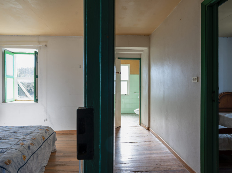 Fotografía de casa para reformar en Bergondo con carpinterías verdes_ distribuidor, y dormitorios + cuarto de baño al fondo