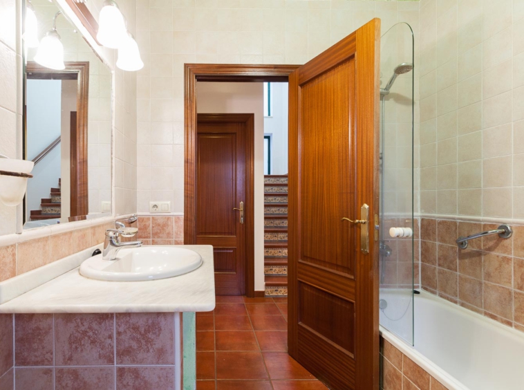 Baño clásico en vivienda unifamiliar en Bergondo_ Puerta abierta desde la que vemos las escaleras de frente