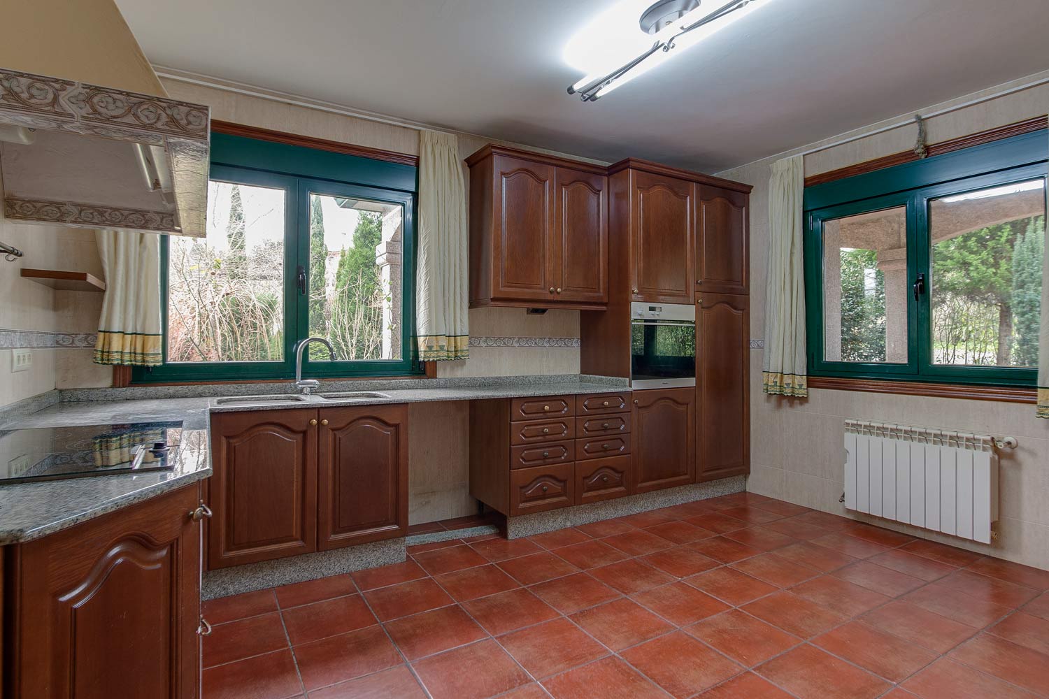 Espacio vacío_ cocina clásica de madera en vivienda unifamiliar en Bergondo con dos ventanas de carpintería verde