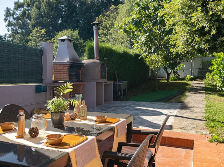 Terraza con mesa y sillas, junto a zona de barbacoa en el jardín