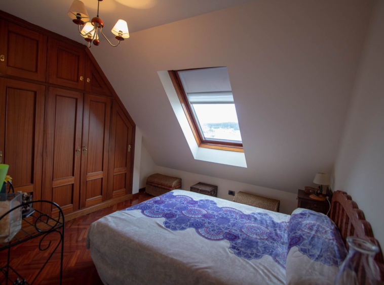 Dormitorio con armario empotrado y ventana velux