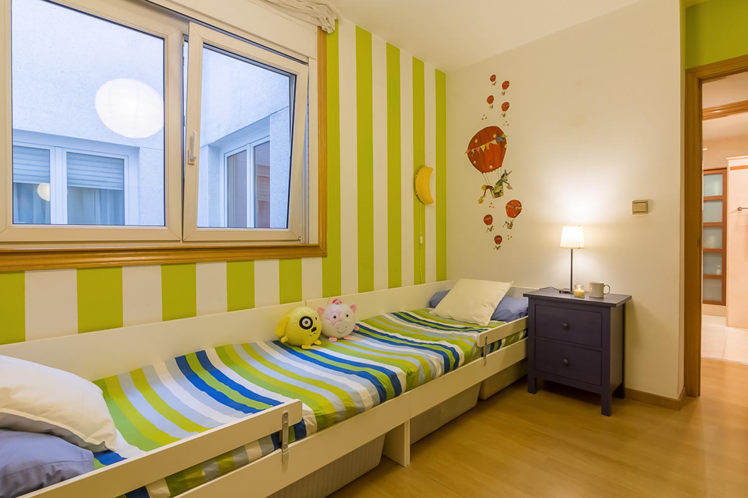 Dormitorio juvenil en tonos verdes y azules_ Camas alineadas bajo ventana oscilobatiente a patio interior