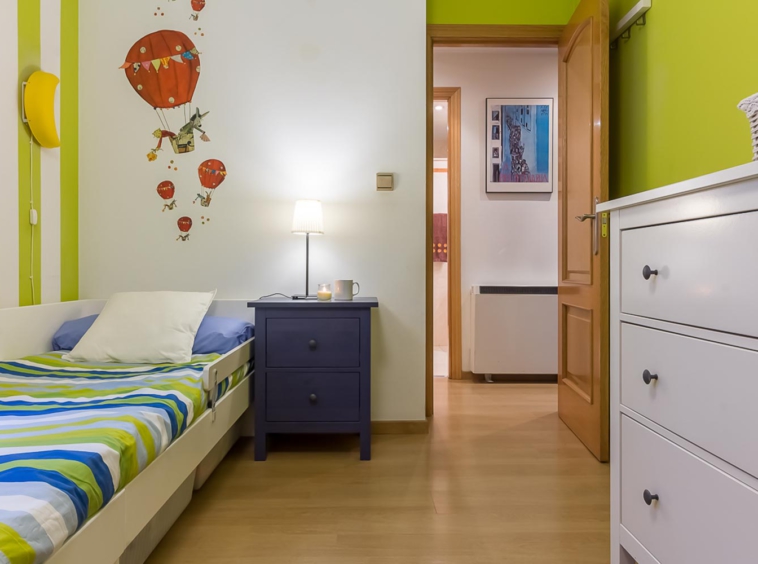 Dormitorio juvenil en tonos verdes y azules con vinilo de globo aerostático rojo en cabecero_ perspectiva hacia pasillo_ Home Staging