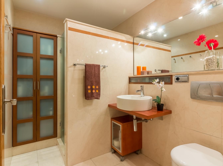 Cuarto de baño con lavabo sobre encimera suspendida y armarios empotrados_ducha separada con tabique que no llega hasta el techo y azulejo de gran formato