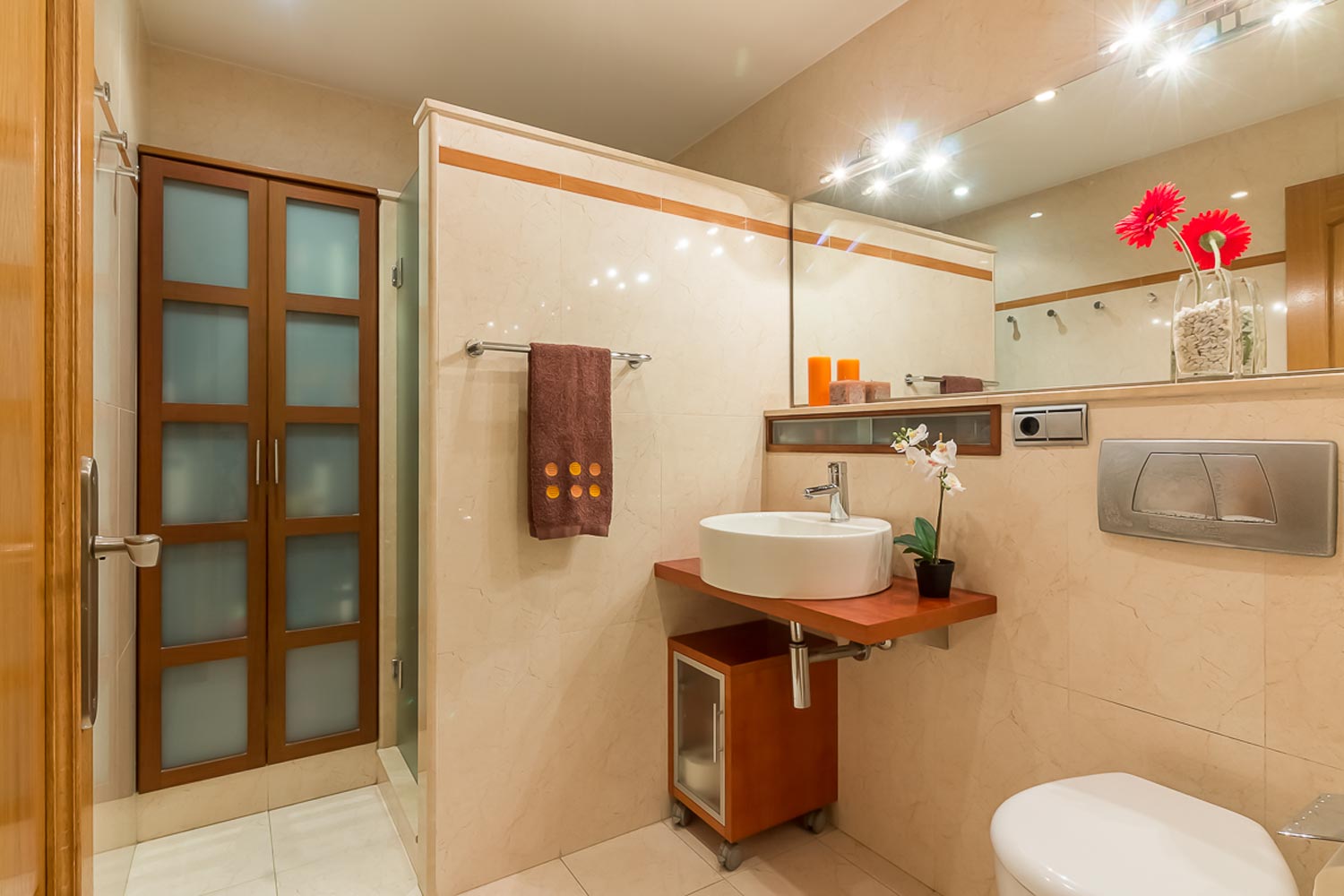 Cuarto de baño con lavabo sobre encimera suspendida y armarios empotrados_ducha separada con tabique que no llega hasta el techo y azulejo de gran formato