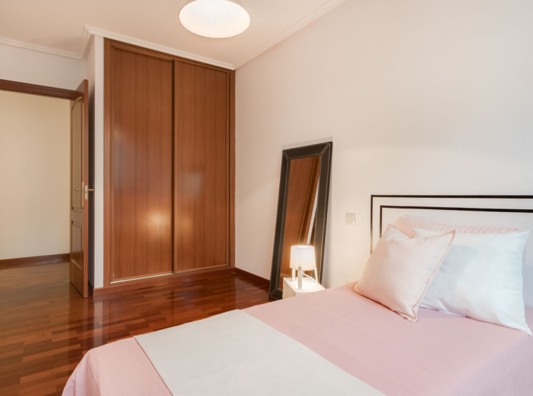 Dormitorio doble con cabecero de vinilo en pared y textiles blancos y rosa palo_ armarios empotrados