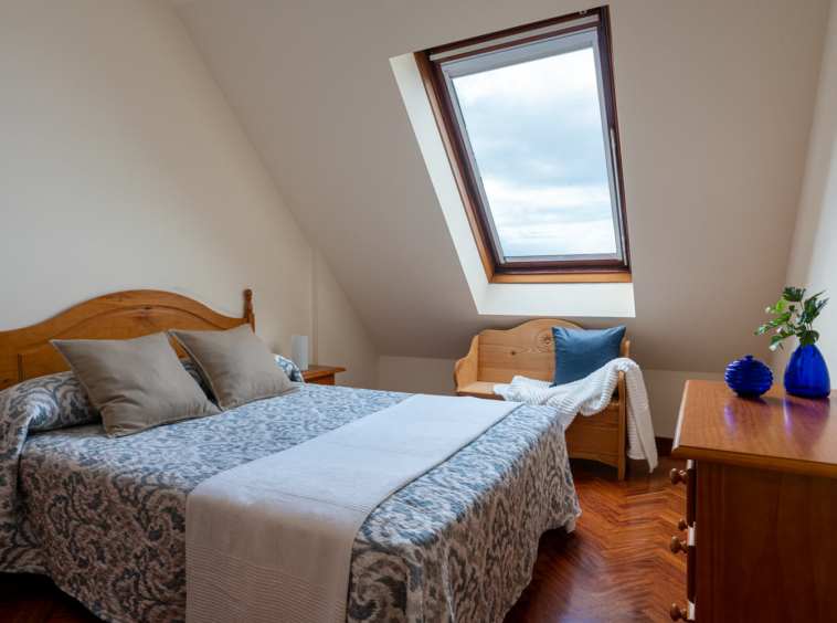 Dormitorio principal con cama de matrimonio y ventana velux