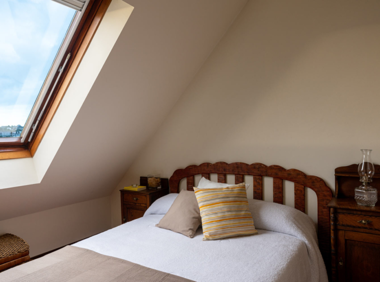 Dormitorio con cama invididual y ventana velux