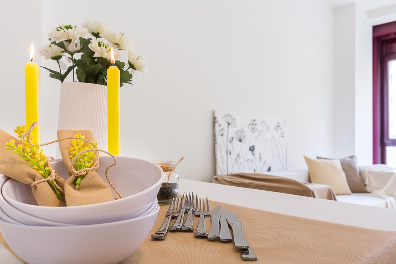 Detalle platos y cubiertos sobre mesa de comedor y velas amarillas_ Home Staging