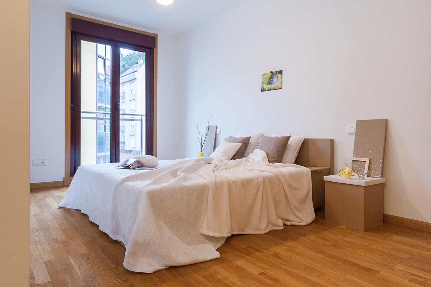 Dormitorio de matrimonio con balcón_ montaje de home staging con mobiliario de cartón y textiles neutros