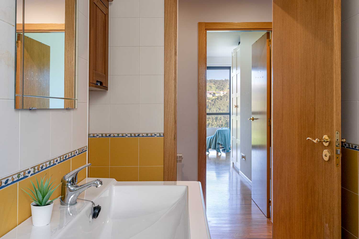 Cuarto de baño blanco y amarillo sencillo y conexión con dormitorio