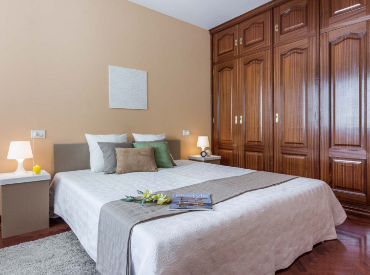 Dormitorio principal con home staging de cartón y textiles neutros_armario empotrado grande de madera