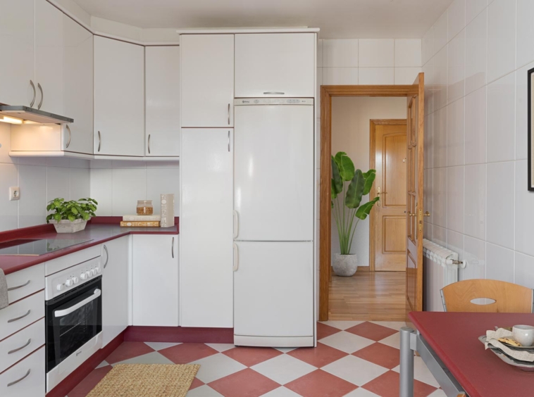 Cocina clásica con mesa roja y electrodomésticos integrados, iluminada y acogedora, en piso en Sada, listo para entrar a vivir.