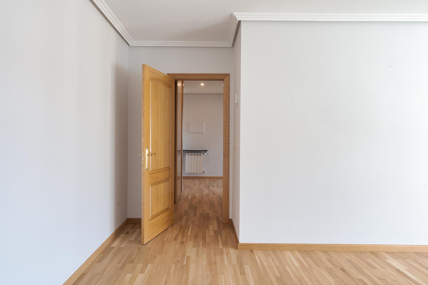 Habitación minimalista con puerta de madera y suelo de parquet en apartamento luminoso en Sada, ideal para crear un hogar a medida
