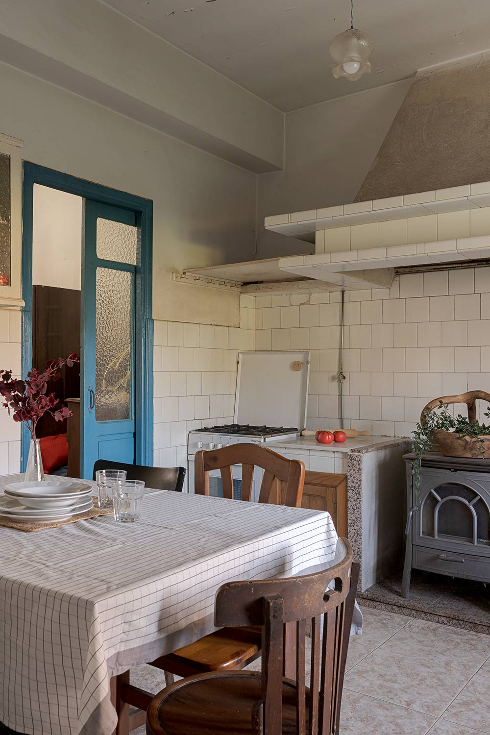 Cocina rústica con mesa de madera, sillas y una estufa antigua, ofreciendo un ambiente tradicional y acogedor en una casa de Bergondo, A Coruña