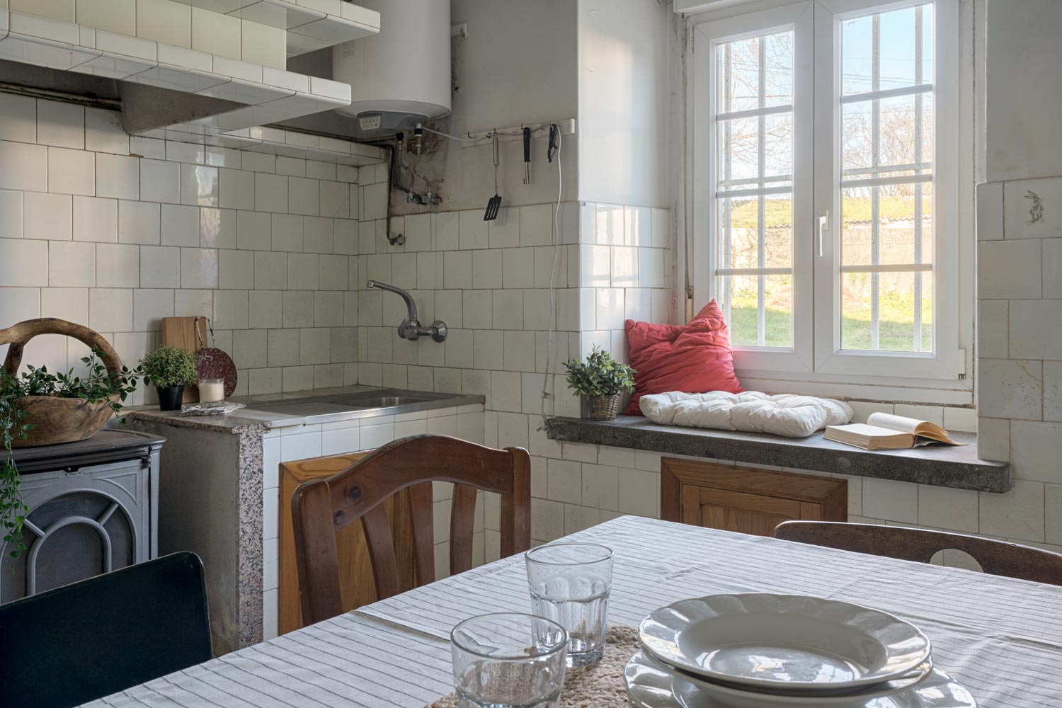 Cocina luminosa con ventana grande, encimera de granito y una estética rústica, ofreciendo un espacio tranquilo y acogedor en una casa de Bergondo, A Coruña.