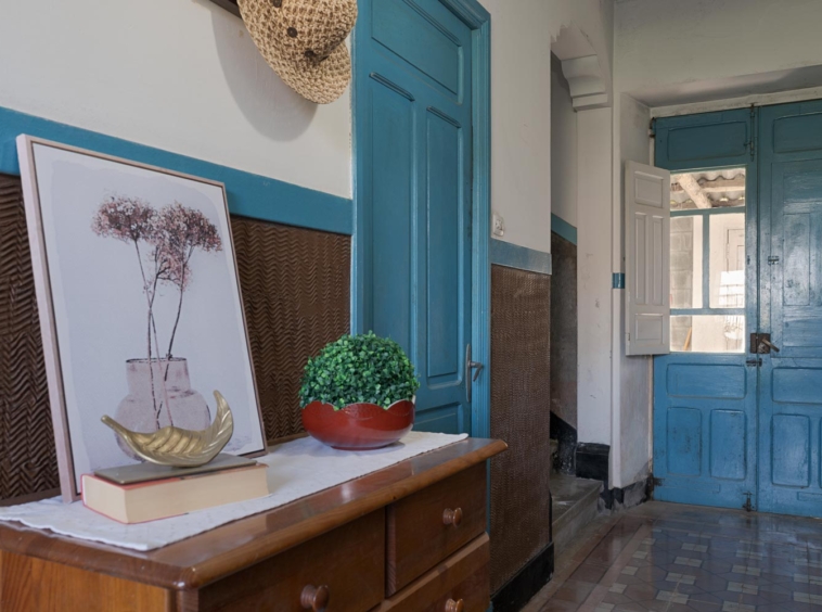 Hall de entrada con puertas de color azul desgastado, una cómoda de madera y decoración rústica que crea un ambiente acogedor en una casa en Bergondo, A Coruña