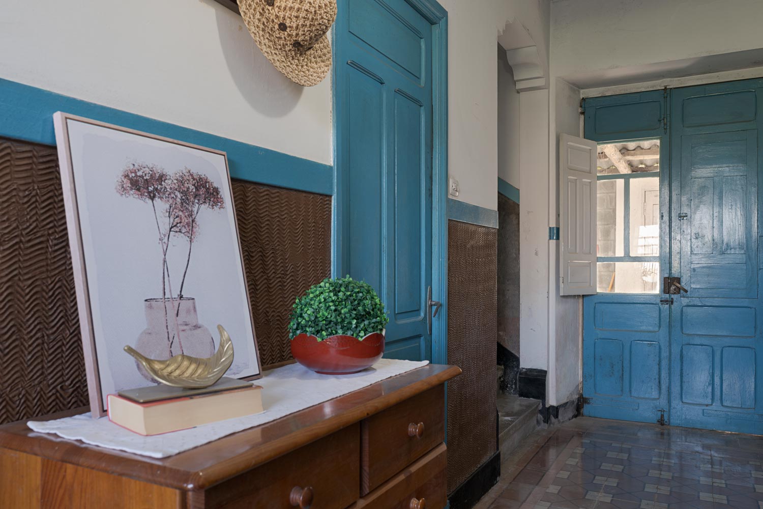 Hall de entrada con puertas de color azul desgastado, una cómoda de madera y decoración rústica que crea un ambiente acogedor en una casa en Bergondo, A Coruña