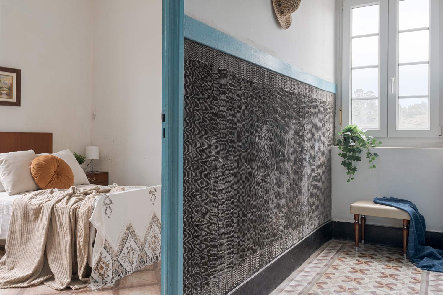 Dormitorio acogedor con cama de madera, detalles decorativos en tonos neutros y luz natural entrando por la ventana, en una casa de Bergondo, A Coruña.