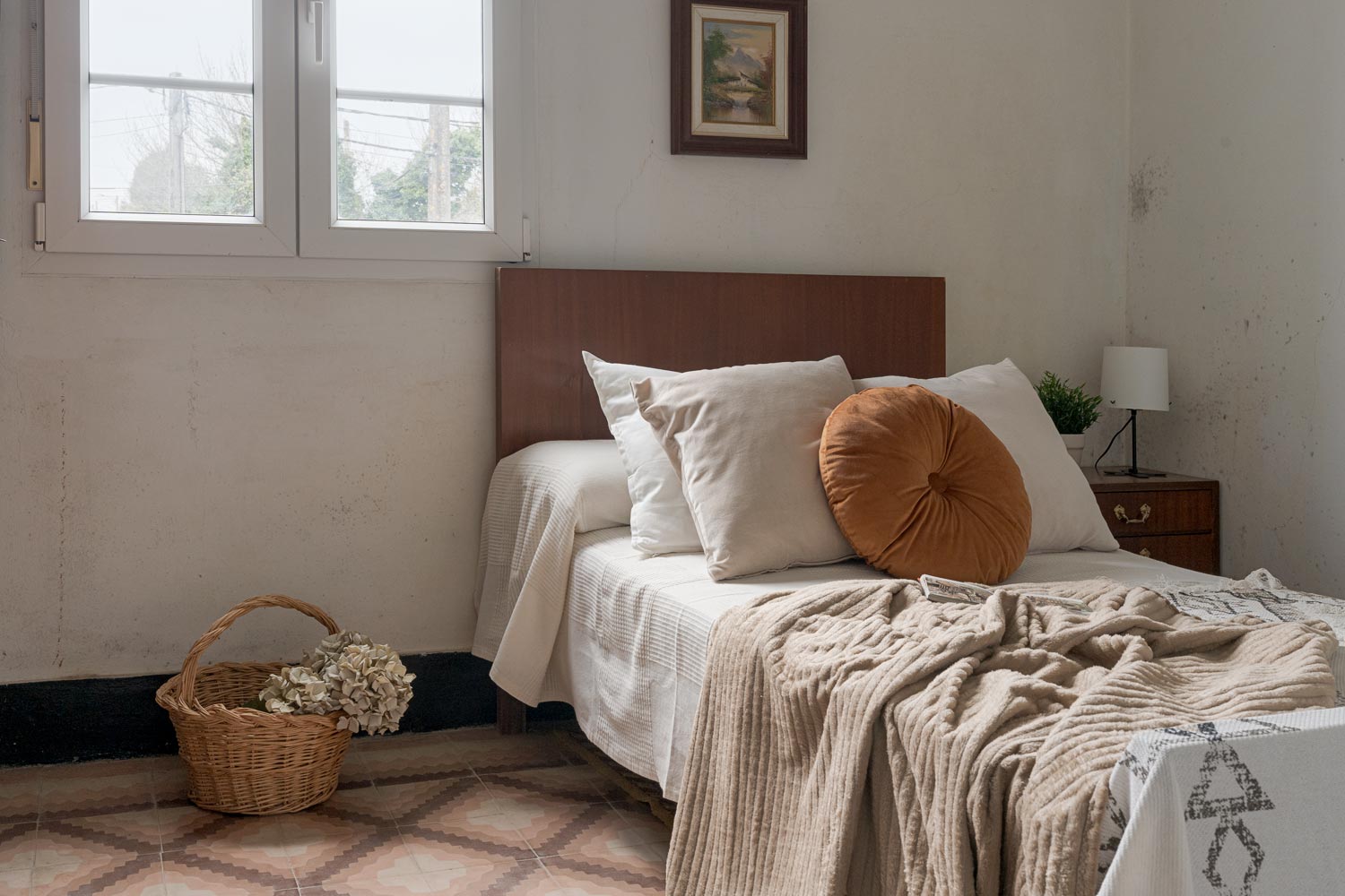 Dormitorio acogedor con cama de madera, detalles decorativos en tonos neutros y luz natural entrando por la ventana, en una casa de Bergondo, A Coruña.