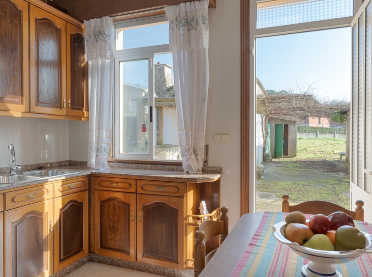 Cocina rústica con armarios de madera y ventana con vistas al jardín.