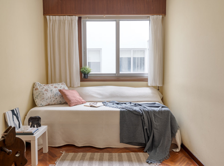 Habitación sencilla con cama individual, ventana grande y decoración minimalista