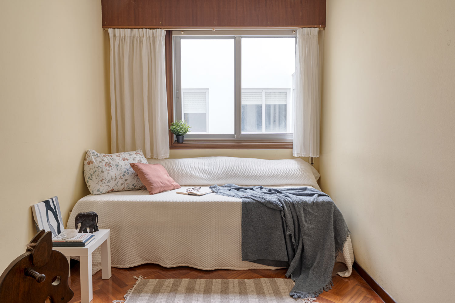 Habitación sencilla con cama individual, ventana grande y decoración minimalista