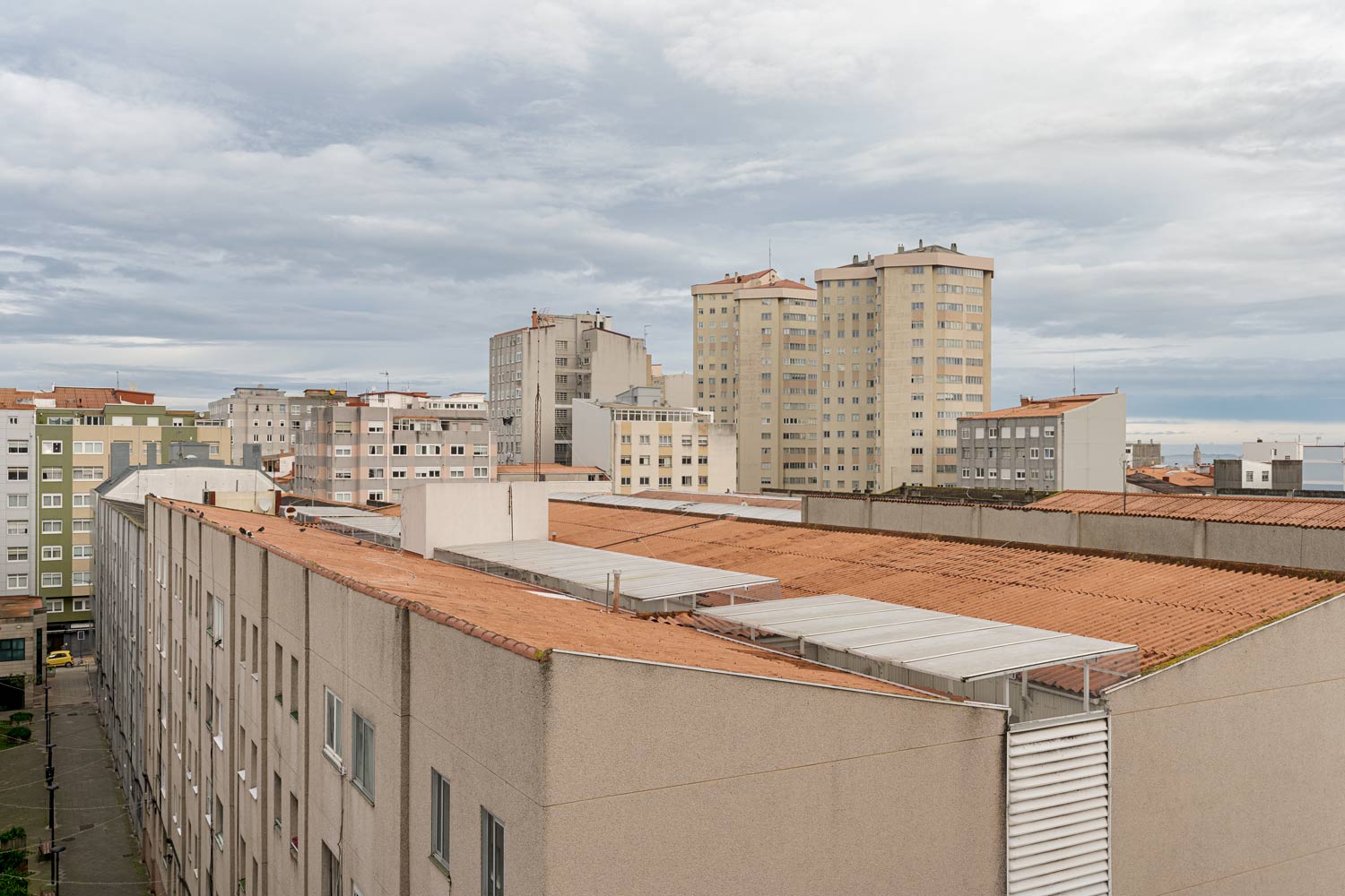Vista urbana de A Coruña con edificios residenciales y techos de tejas bajo un cielo nublado.