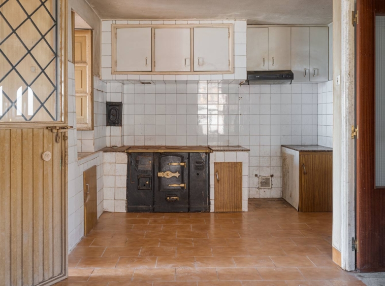 Cocina antigua con bilbaina y azulejos en blanco en una casa para restaurar en Sada