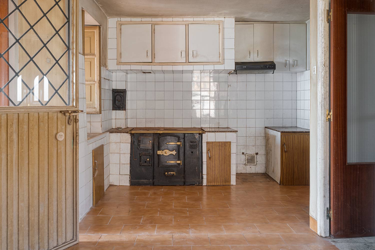 Cocina antigua con bilbaina y azulejos en blanco en una casa para restaurar en Sada