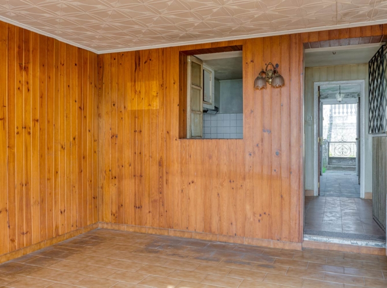 salón con paredes forradas en madera en casa para restaurar en Sada