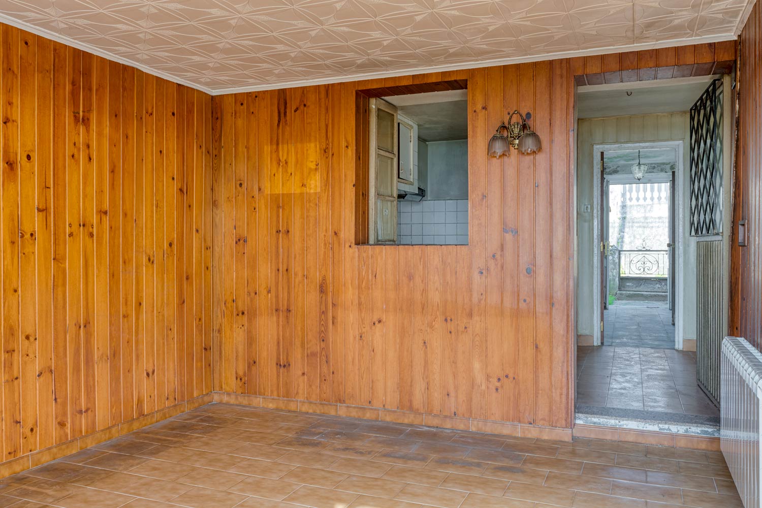 salón con paredes forradas en madera en casa para restaurar en Sada
