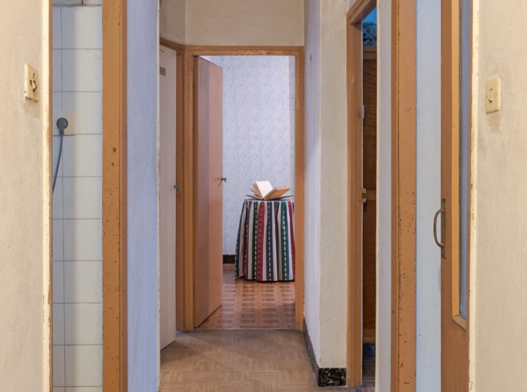 Largo pasillo residencial con puertas de madera abiertas que conducen a varias habitaciones, con una alfombra colorida al final en A Coruña