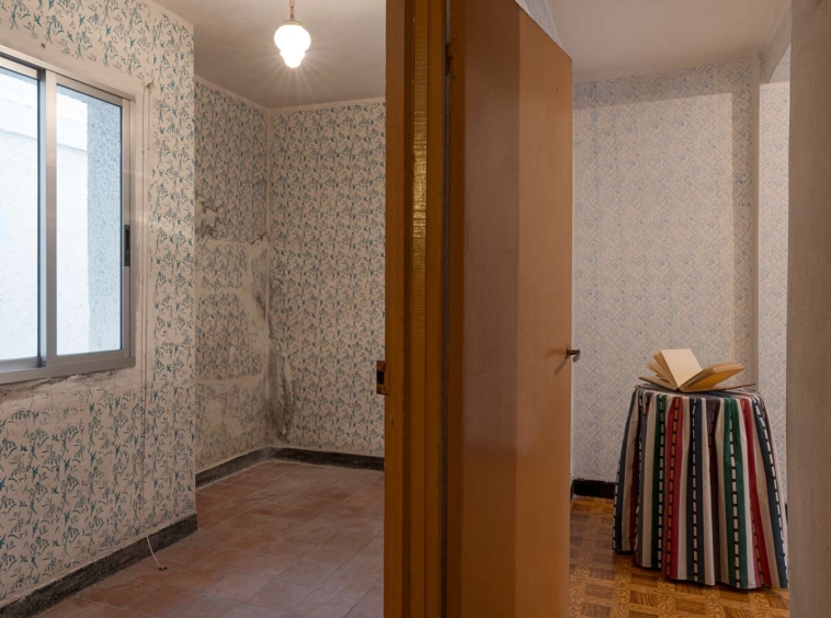 Habitación vacía con paredes de papel tapiz de patrones florales y ventana con vistas a edificio vecino en A Coruña