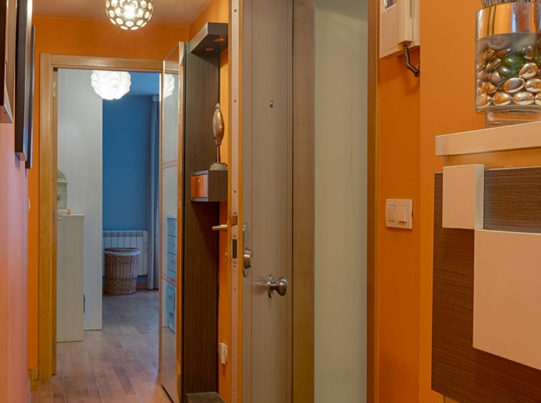 Pasillo acogedor con paredes naranjas y suelo de madera, decorado con lámparas esféricas y un espejo en Sada