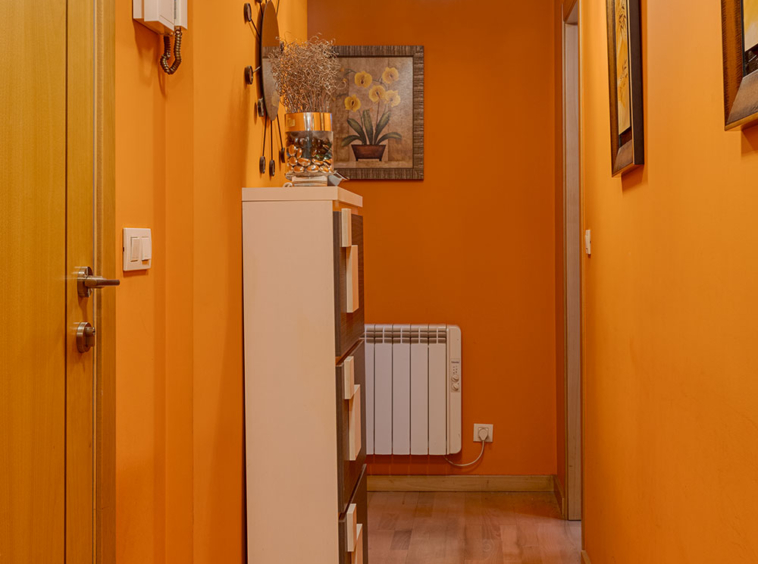 Pasillo acogedor con paredes naranjas y suelo de madera, decorado con lámparas esféricas y un espejo en Sada