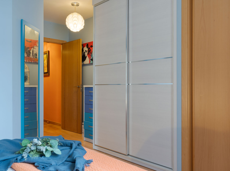 Habitación acogedora con paredes azules con ropa de cama en tonos naranja y azul, en Sada