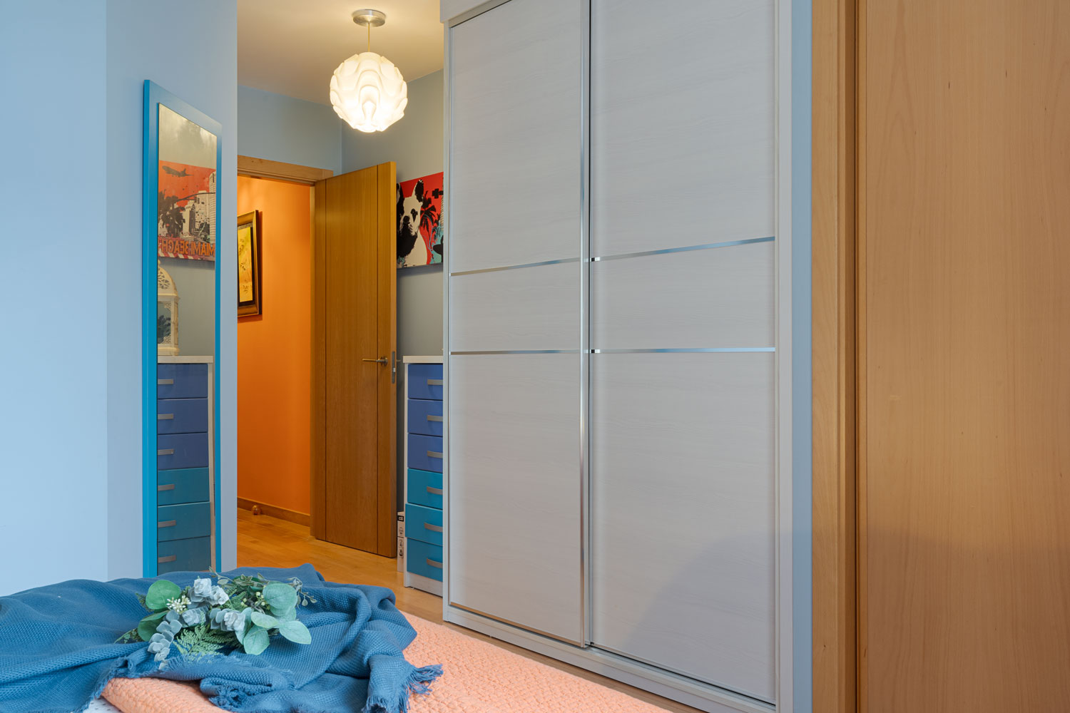 Habitación acogedora con paredes azules con ropa de cama en tonos naranja y azul, en Sada