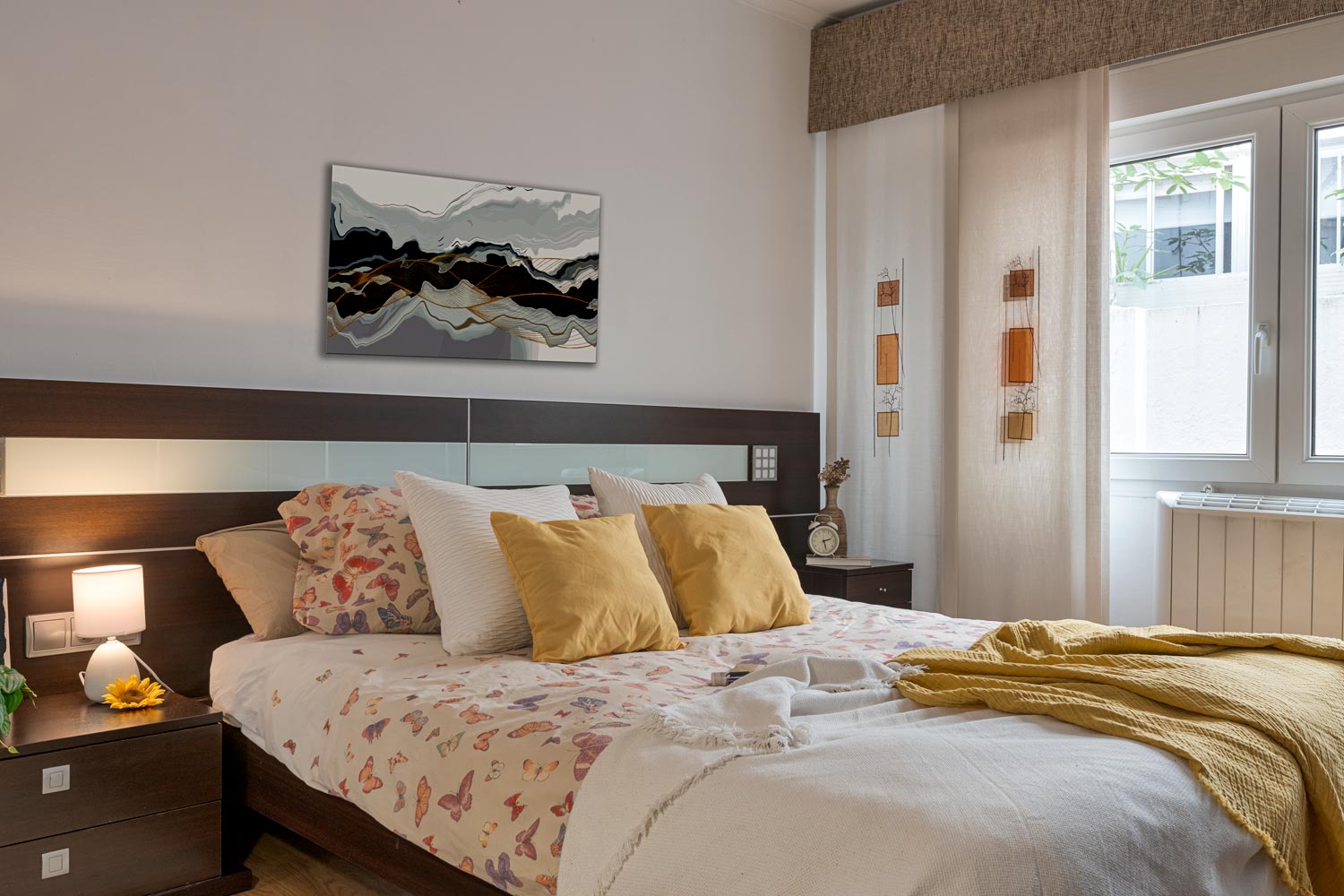 Dormitorio acogedor con una cama de matrimonio con ropa de cama azul, una mesita de noche de madera con una lámpara, un cuadro abstracto en la pared y una ventana con vistas